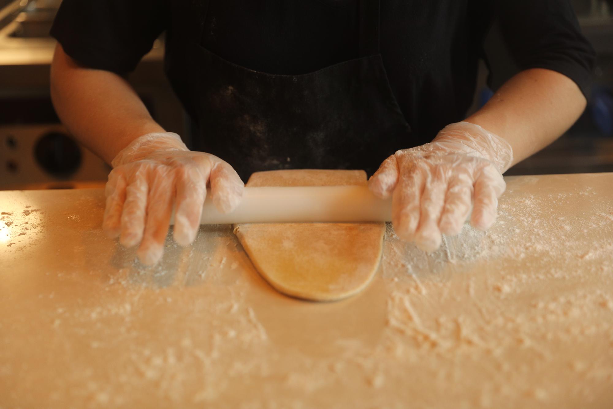 Hands preparing dough on wooden board